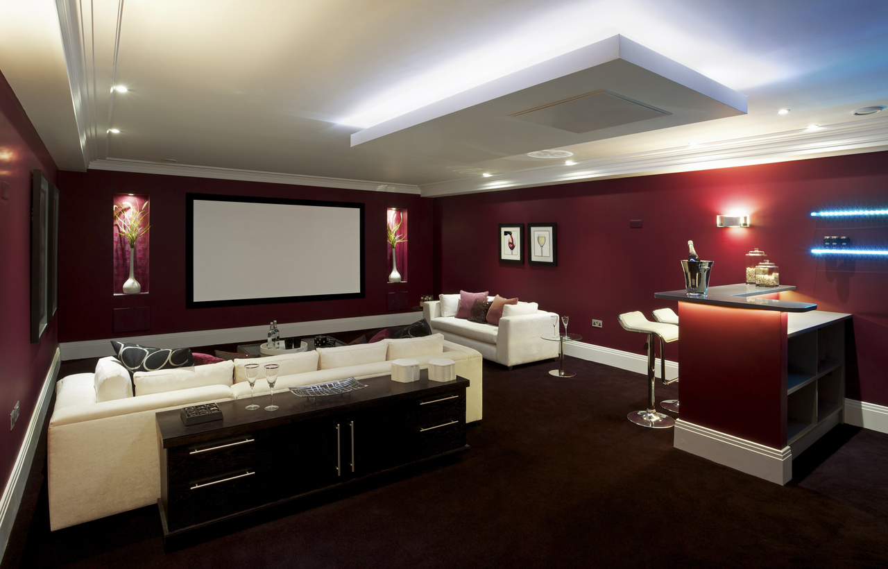 Luxurious finished basement with a home theater setup, comfortable seating, and a stylish bar area, highlighting a prime way to add functional living space in Oak Ridges and the GTA.